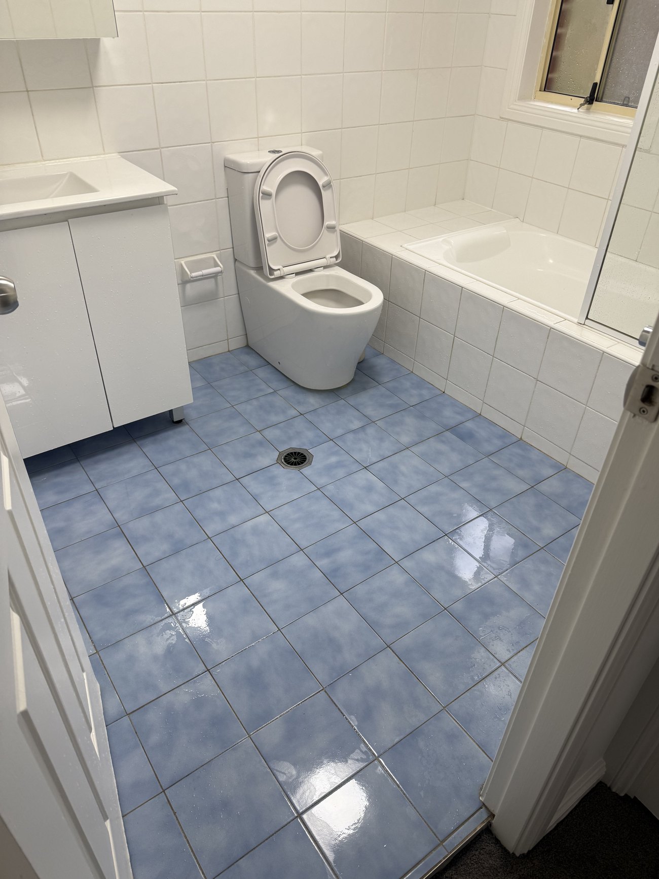 Bathroom with blue tile floor cleaned, toilet and bath